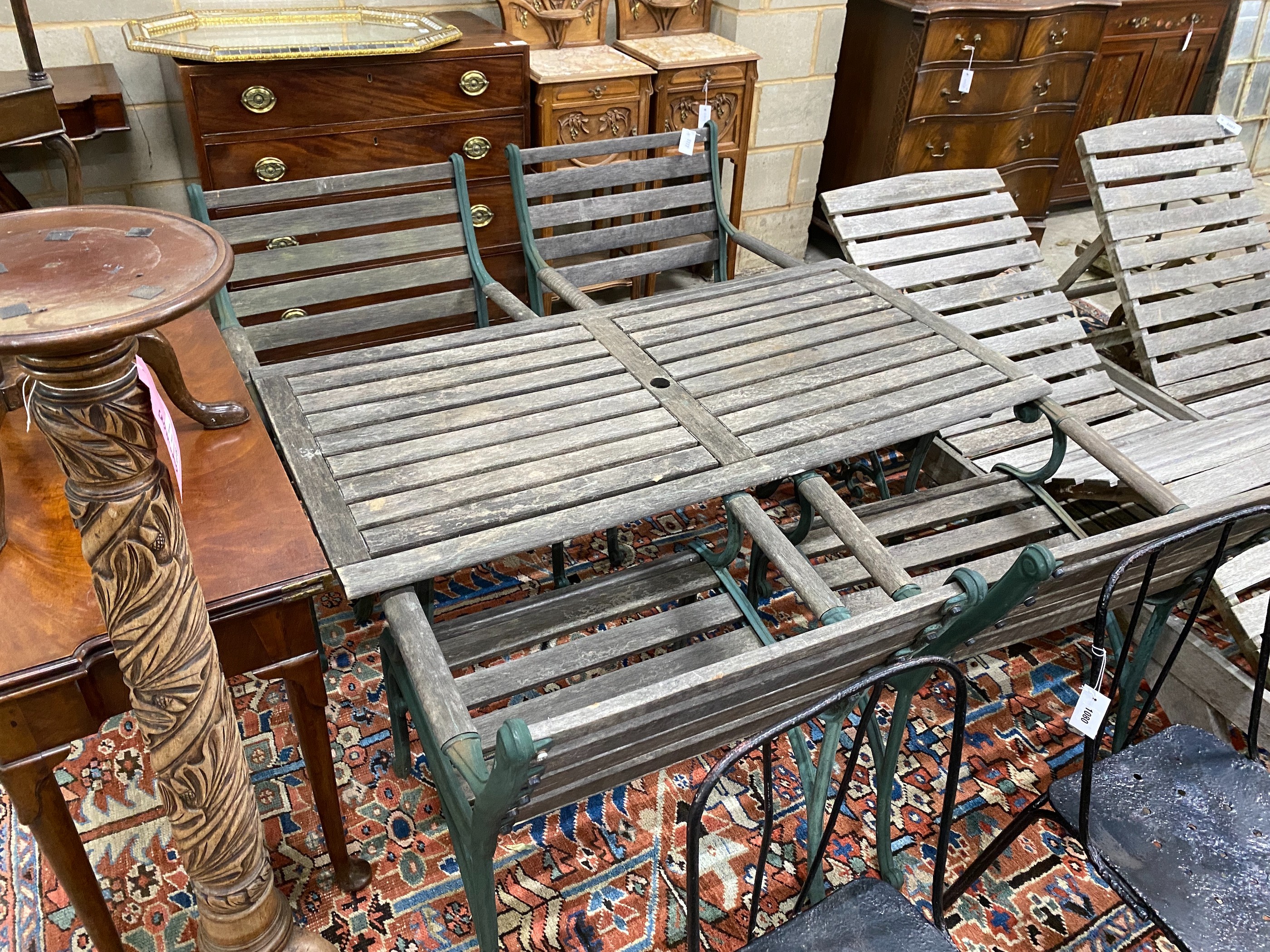 A rectangular slatted wood and cast metal garden table, length 137cm, depth 67cm, height 64cm together with four similar elbow chairs